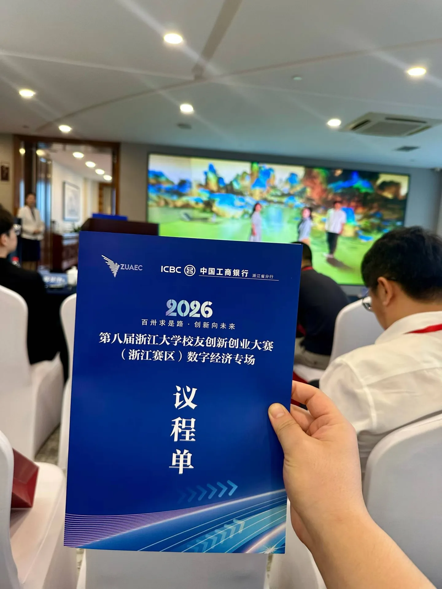 数字经济专场现场照片，前景为赛事议程单，背景为现场会场